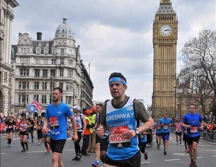 Runner in the London Marathon passing Big Ben, wearing a Greenway jersey and bib number 46284