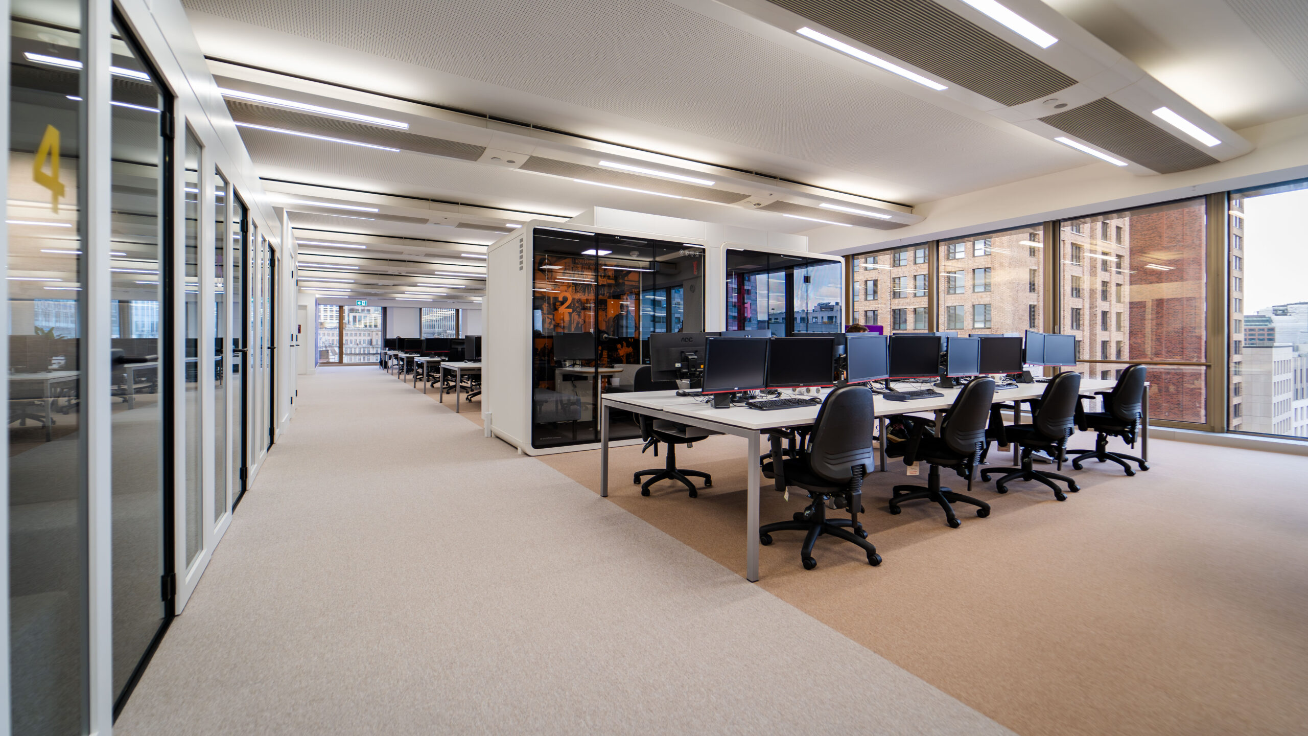 Modern open-plan office with natural lighting, acoustic pods, and ergonomic seating designed to support a neuroinclusive work environment